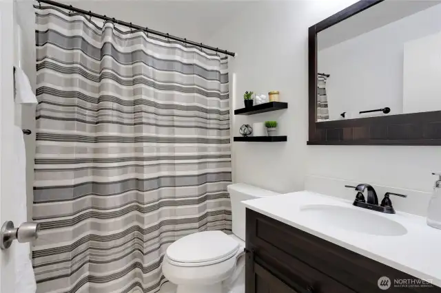 Main hallway bathroom conveniently located between the second and third bedrooms, featuring a new vanity and mirror, plus a full tub and shower combo perfect for family and guests.