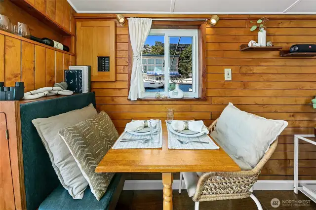 In the mess, rich wood paneling and built-in seating create a warm, intimate spot for dining or working, framed by a double-pane window that opens to fresh lake breezes.