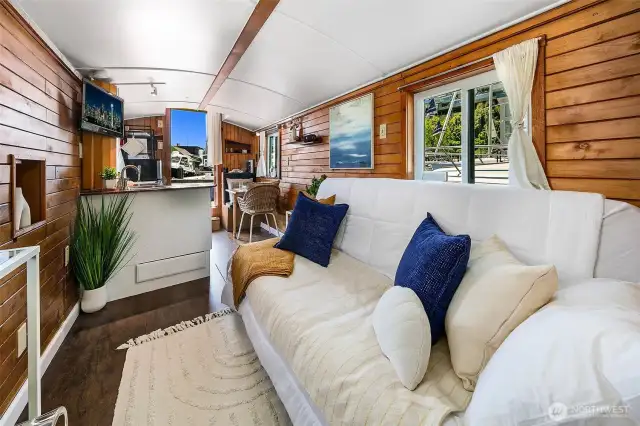 A cushioned settee lines the saloon, bathed in natural light from double-pane windows that open to fresh lake breezes — a relaxed spot for reading, conversation, or simply watching the water.