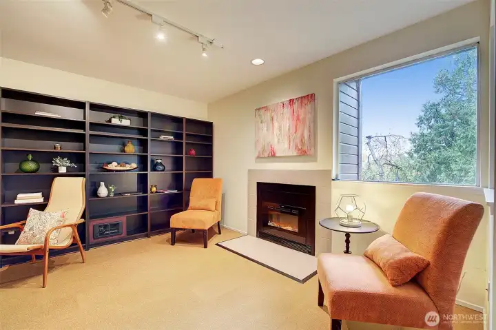 Lower level family room with built in bookshelves and electric fireplace.