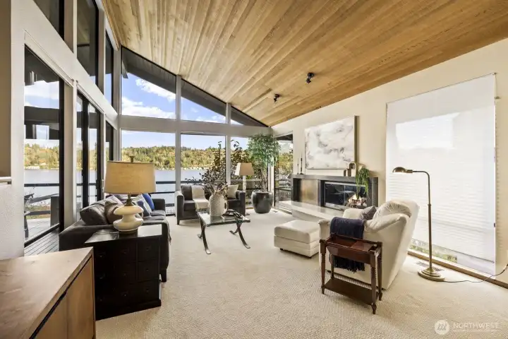 Living room features window wall to capture amazing lake views, cozy gas fireplace and vaulted ceiling