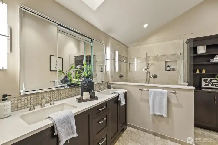 Light filled primary bath with large walk in dual head shower, dual vanity +skylight