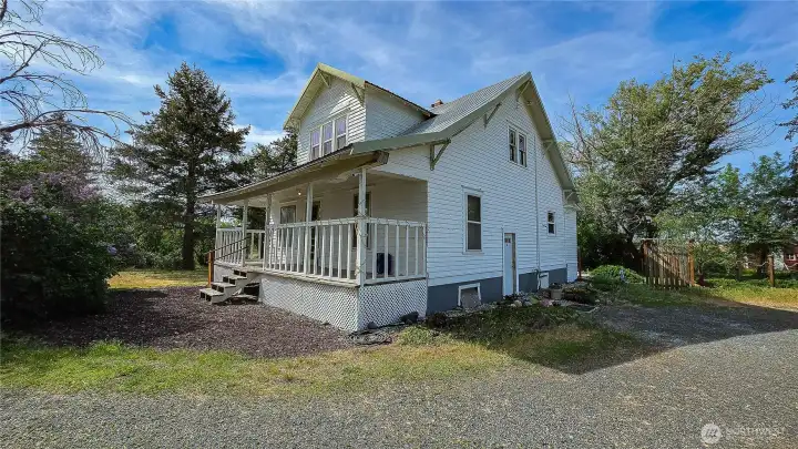Welcome to your charming classic farmhouse featuring a welcoming covered front porch, perfect for enjoying the peaceful country setting. This picturesque property boasts classic character, a spacious lot framed by beautiful mature trees, and ample gravel parking. Looking NW from the SE Corner of the home.