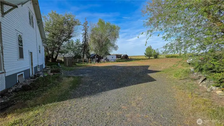 Incredible acreage property featuring wide-open spaces and multiple outbuildings for your homestead or hobby farm. The side yard highlights the massive lot, endless outdoor potential, and a picturesque rural setting. Looking NE from the SW area of the property.