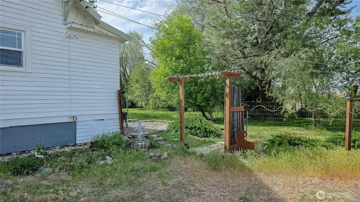 Charming garden entrance and fenced yard! The rustic trellis gate, wire fencing, and lush mature trees offering a truly peaceful country setting. Looking NW from the East side of the home.