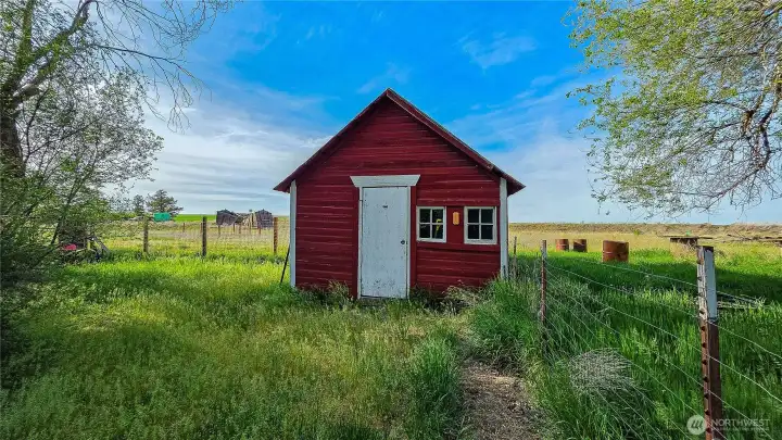 Every tinkerer's dream! The charming red hobby shed is perfect for garden projects, a home workshop, or extra storage on this incredible acreage. Looking North from NW area of the property.