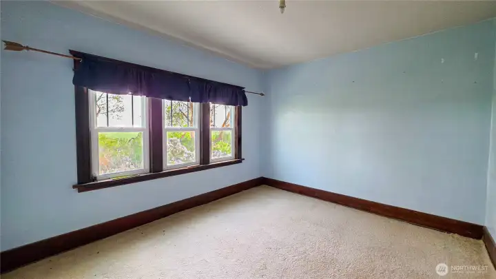 Bedroom 2, located upstairs on the southwest side of the home, featuring a large triple window that provides abundant natural light. of the house.