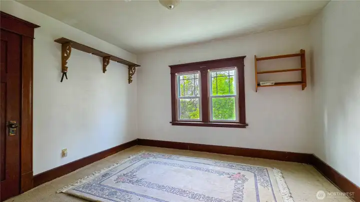 Northwest-facing upper-level bedroom highlighting a double window with exterior views, carpeted flooring, and built-in display shelves.house upstairs.