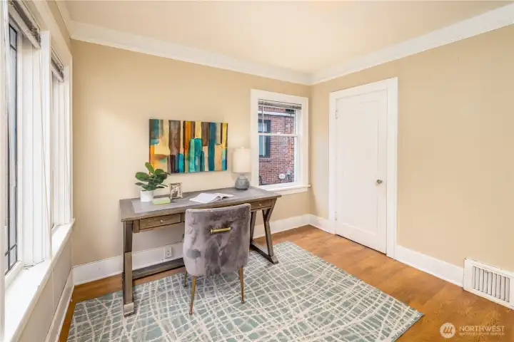 Main floor bedroom with rich hardwoods and large picture windows.