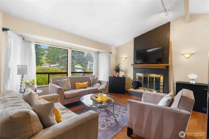 Light-filled living room with soaring ceilings, hardwood floors, and a cozy fireplace.