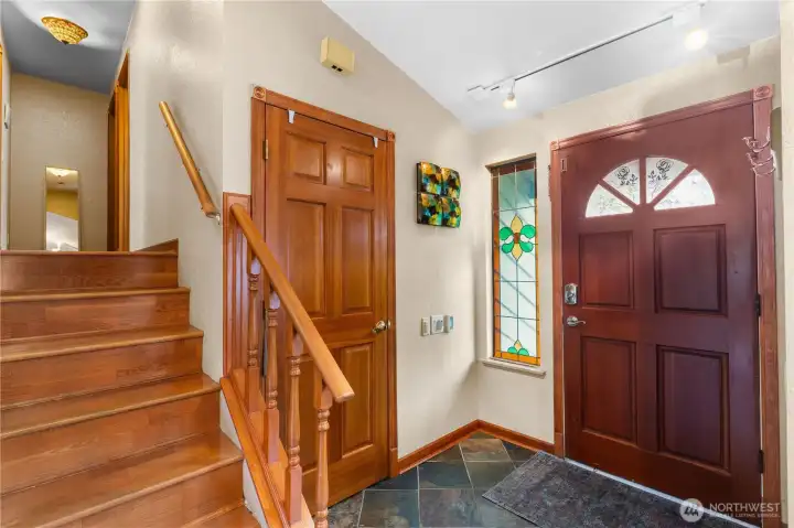 Inviting foyer with hardwood staircase and custom stained-glass accents