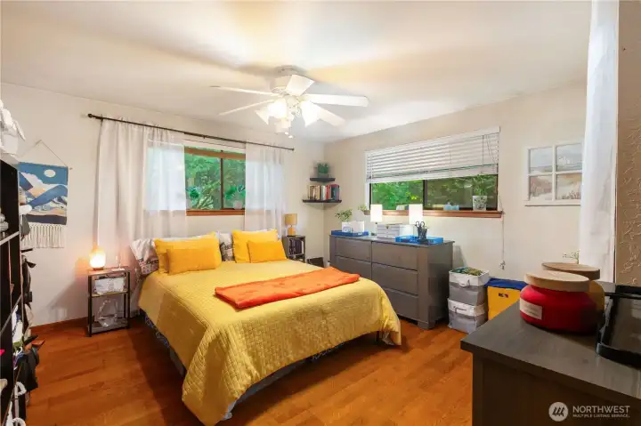 Spacious primary suite with hardwood flooring and backyard  views.