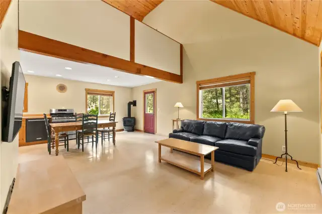 Open-concept main floor integrates kitchen, dining, and living spaces.  Vaulted ceilings with exposed beams add warmth and architectural interest.