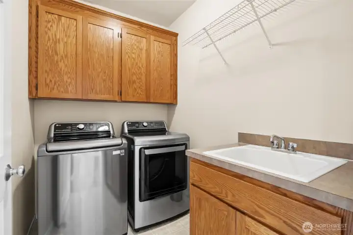 The main floor laundry room offers ample cabinet storage, a deep utility sink, and plenty of space to hang and organize items.