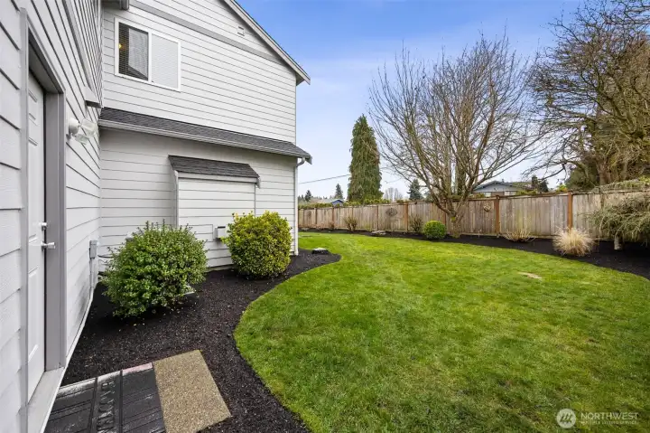 The backyard features lush green grass and a convenient man door providing direct access to the garage.