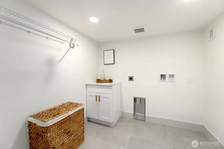 Spacious lower level laundry with non-conforming ceiling heights with shelving + storage.
