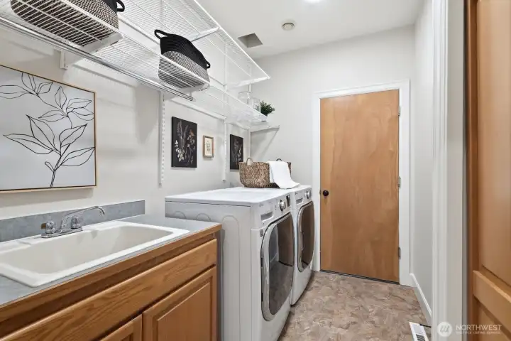 Laundry room connects the home to the garage and includes a utility sink, cabinetry, and closet.