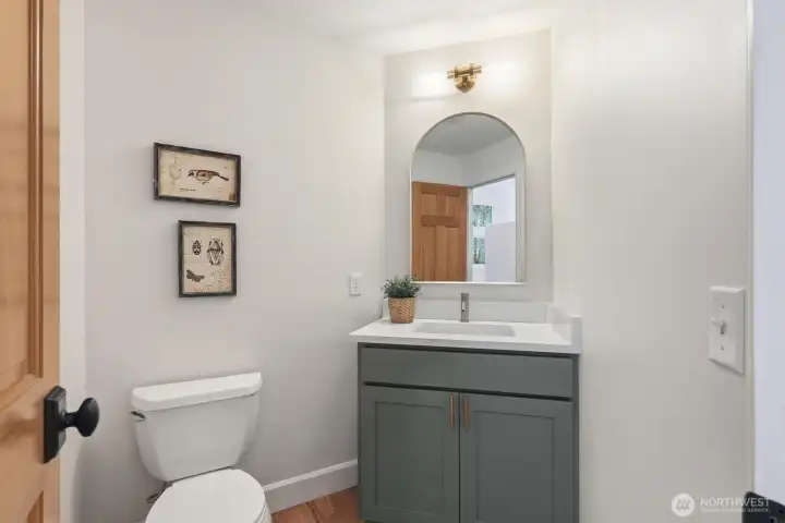 Updated main-floor half bath featuring new vanity, countertop, sink, mirror, and modern lighting.