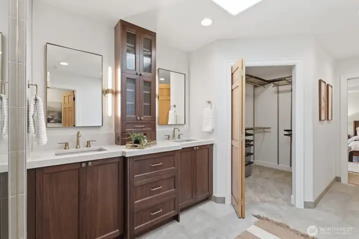 Primary bath with dual sinks and vanity tower, designer lighting and tile, spa-style shower, heated floors, and enclosed water closet.