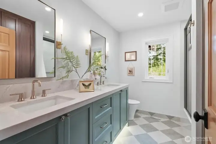 Professionally designed guest bathroom offering dual sinks, designer tile and lighting, and built-in linen storage.