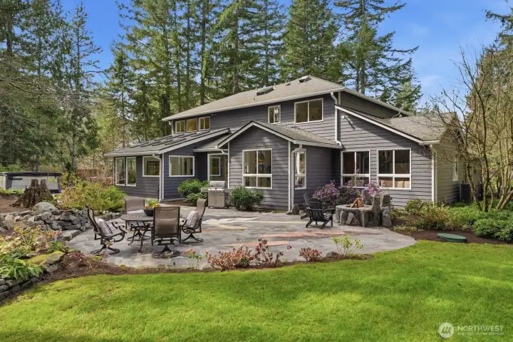 Custom stone patio offering a built-in gas fire pit, steps connecting to other yard areas, and a luxurious built-in salt water hot tub.
