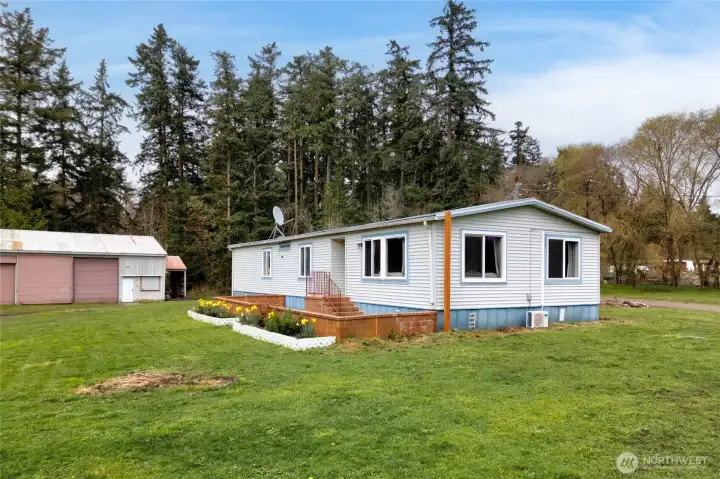 Charming single-level manufactured home set on spacious acreage, featuring a peaceful rural setting with mature trees and open green space. The property includes a large detached shop/garage, ideal for storage, hobbies, or equipment, offering the perfect blend of country living and functionality.