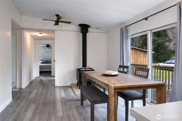 Warm and inviting dining space with a rustic wood-burning stove, perfect for cozy gatherings. Sliding glass doors lead to an outdoor deck, seamlessly blending indoor and outdoor living.