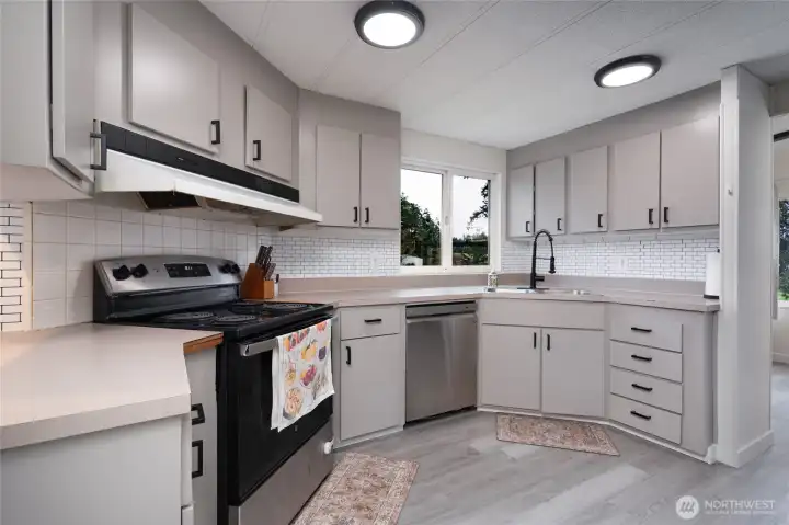 Updated kitchen with modern cabinetry, subway tile backsplash, stainless steel appliances, and ample counter space. Bright windows provide natural light, making this a functional and stylish cooking space.