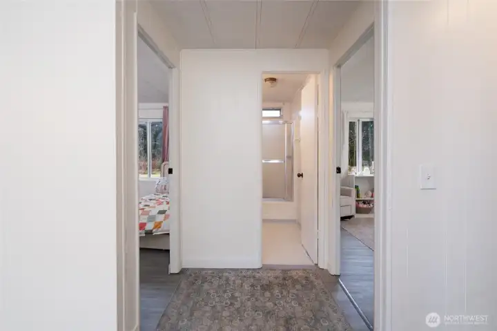 Central hallway connecting multiple bedrooms and a bathroom, offering a practical layout for privacy and convenience. Clean finishes and consistent flooring throughout.