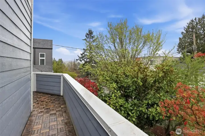 Private deck off primary bedroom is protected from street view by mature landscaping.