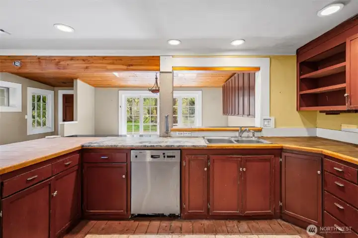 Functional kitchen footprint with peninsula seating and plenty of cabinetry ready for a refresh. Open sightlines to living area and outdoors enhance the layout’s potential.