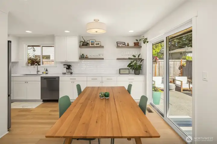 Spacious dining area with large sliding glass doors, indoor-outdoor living access, custom floating shelves, and abundant natural light.