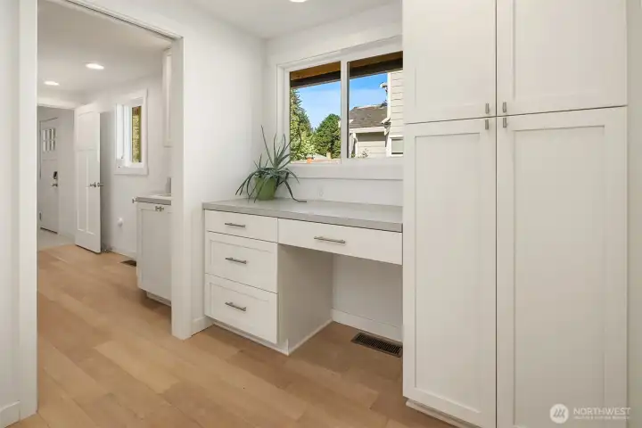 Built-in workstation and storage area with custom cabinetry, quartz countertop workspace, and convenient organization for remote work or household management.