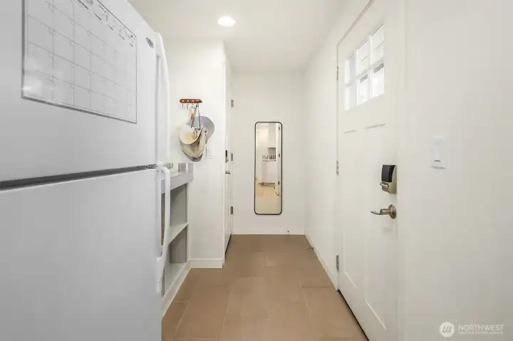 Practical mudroom entry with durable tile flooring, storage cubbies, additional refrigerator space, and direct exterior access.