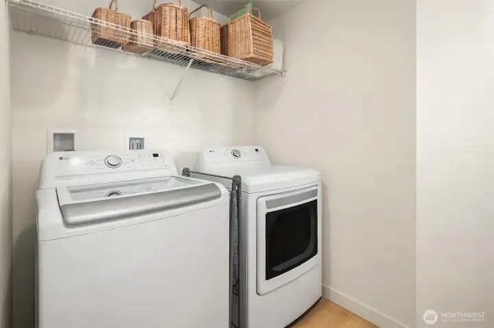 Dedicated laundry room with full-size washer and dryer, overhead storage shelving, and functional utility space.