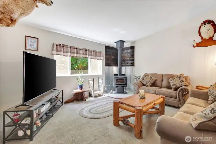 Spacious living space with view to the back porch and back yard. The updated woodstove is a wonderful addition to this tranquil setting.
