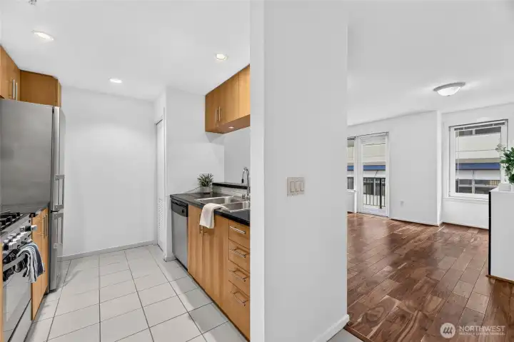 The galley kitchen features wood cabinets, stone tiled counters, 2021 gas range and 2024 microwave. The galley kitchen features wood cabinets, stone tiled counters, 2021 gas range and 2024 microwave.