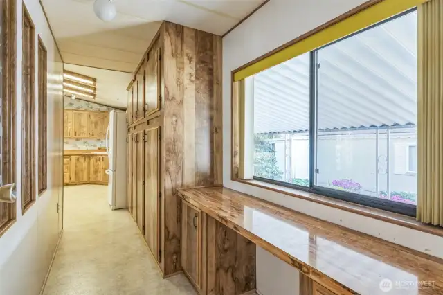 The hallway looking out from the laundry room leading into the kitchen. On the immediate right is the built-in desk feature and a literal wall of cabinets.