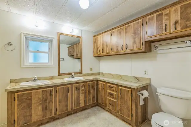 En-suite bath with tons of cabinets for storage along with dual sinks.