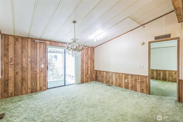 Dining room with a beautiful chandelier and a slider to the covered front porch. The primary suite entrance is on the right.