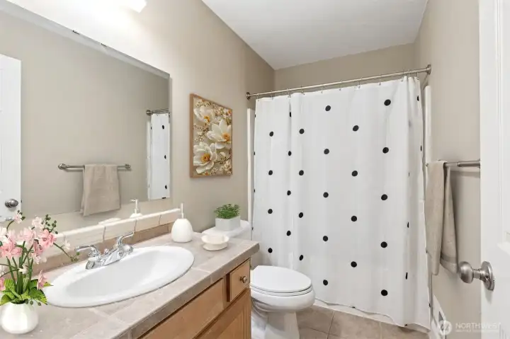 Upstairs, this full bathroom serves the other 3 bedrooms well, with tub surround and storage vanity, plus easy-care tile flooring, all in lovely, neutral tones.