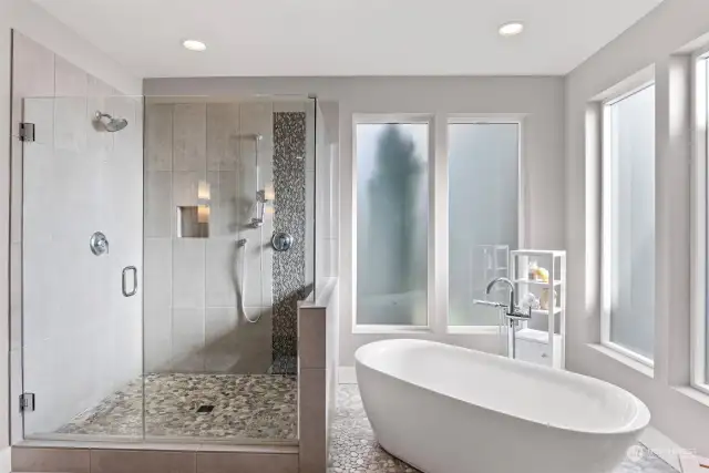 Glass shower doors with tile floors & wall.