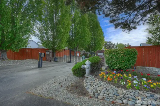 The lovely landscaped entry to Crestview Village features sturdy, double-swing iron gates sitting between well-constructed brick pillars.