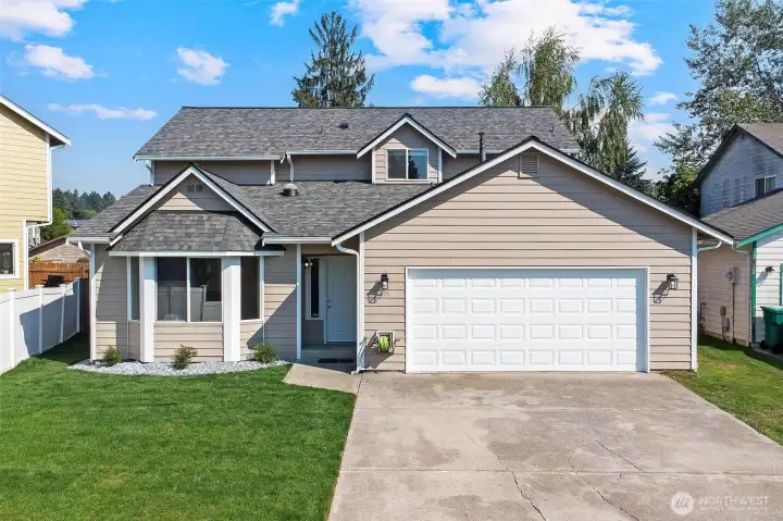 Curb appeal with fresh paint, pressure-washed driveway, stonework, and shrubs.