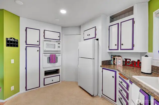 Wall microwave and oven with pantry for all your cooking needs. Splash of color here and there. Access door into the utility room and to the carport area.