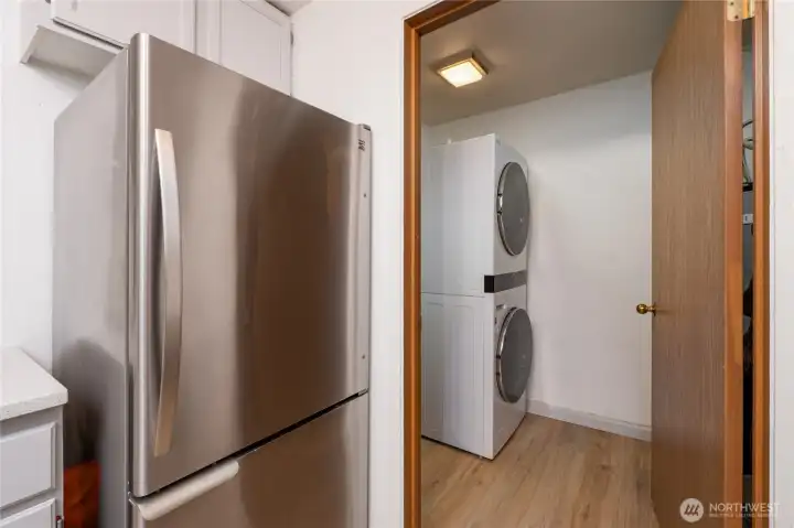 Laundry room with stacked washer dryer, water heater, and plenty of storage.