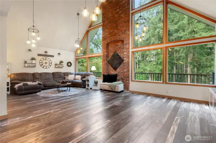 Large oversized living room with masonry wall in the center of a wall of windows facing the front of the home.