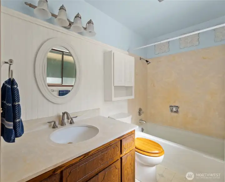 Primary bathroom, with newer corian countertop and solid surface bathtub surround.