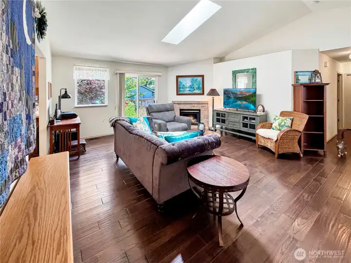 Large open great room with vaulted ceilings and skylight. Updated wood flooring and gas fireplace keep things cozy. Slider provides access to private patio and lovely rear yard.