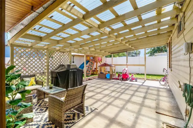 You'll just love this covered back patio! The opaque, corrugated cover allows light in and helps keep the heat or snow out!  Perfect for BBQs and social gatherings.